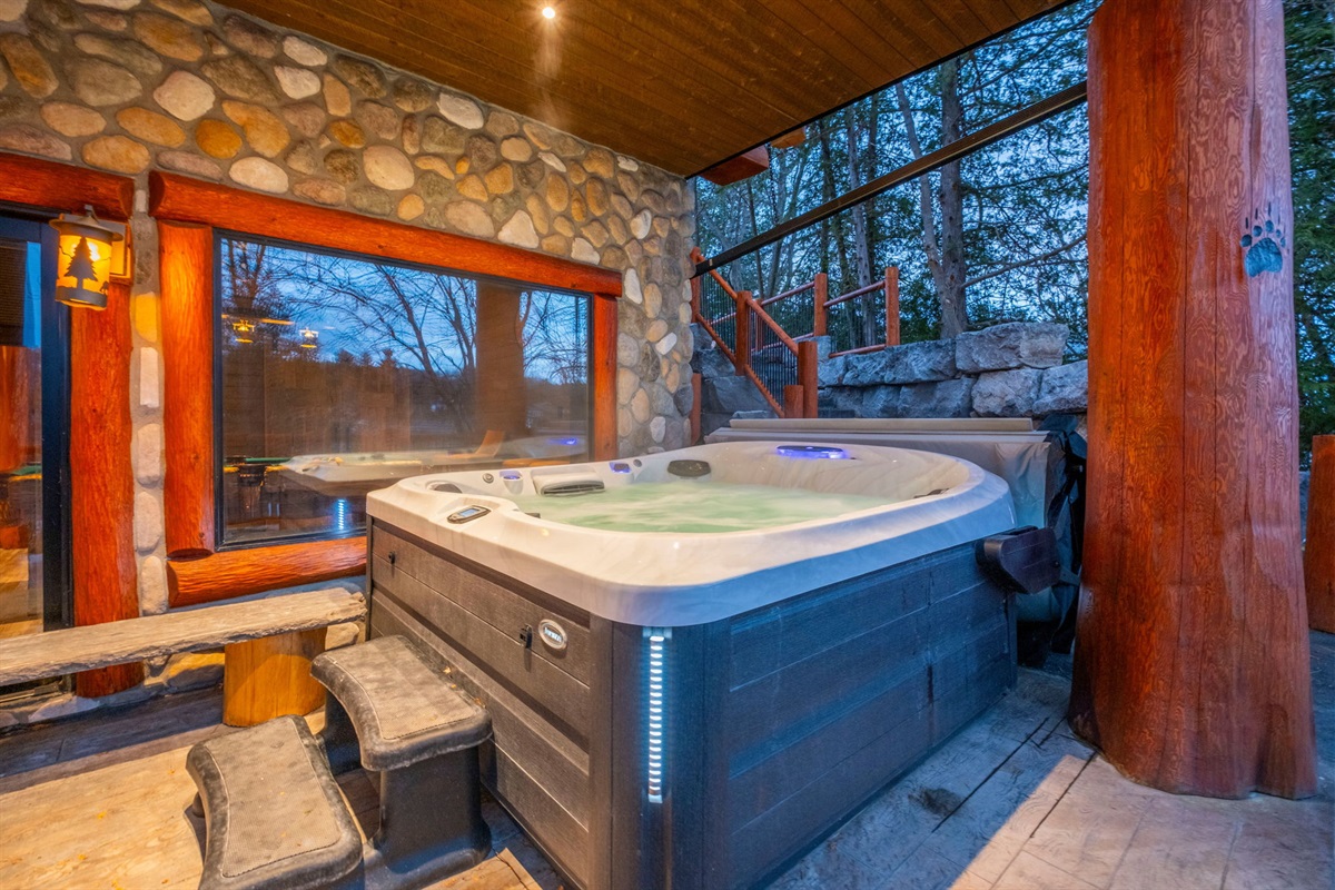 Private outdoor Jacuzzi with lake views — enjoy soothing jets surrounded by natural stone and handcrafted logs.