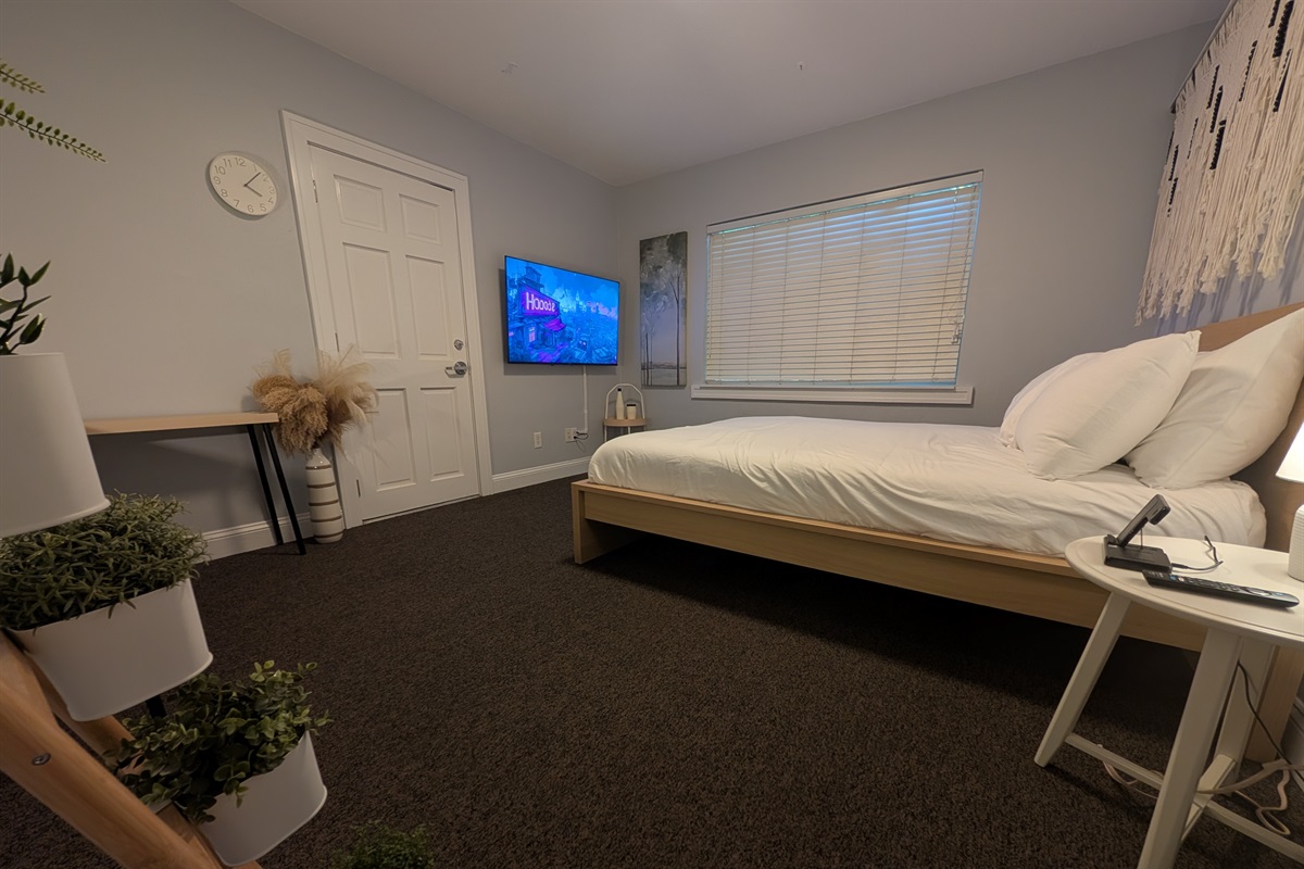 Guest bedroom with queen bed, desk and smart tv