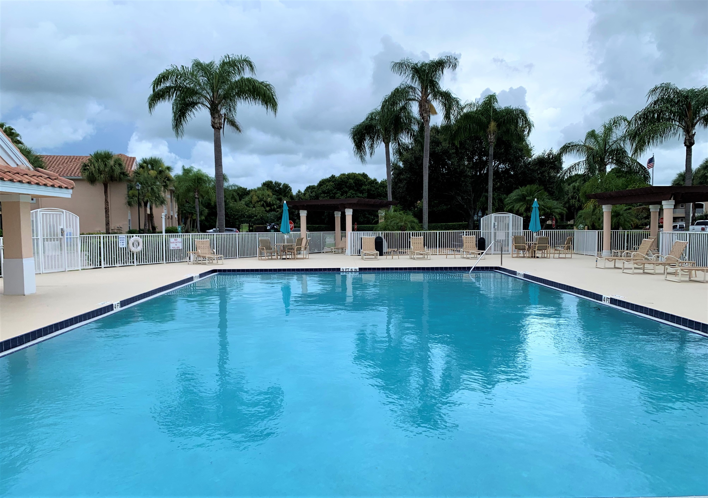 Bright community pool area with lounge seating, umbrellas, and a relaxing resort-style atmosphere.