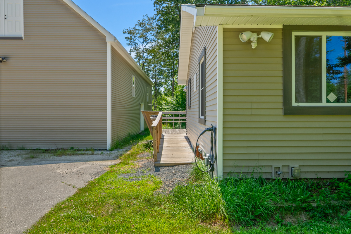 View the Level 2 EV charger mounted beside the long entry ramp. This layout path leads directly up to the outdoor deck, connecting your parked vehicle straight to the entry door, propane fire table, and private 6-person hot tub.