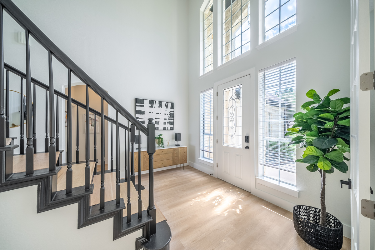 Sunlit entryway welcomes you home — floor-to-ceiling windows meet a sleek modern staircase.