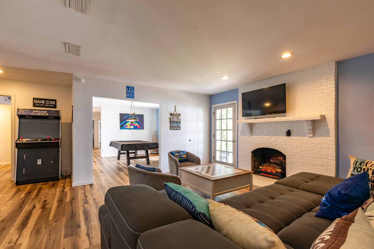 The downstairs living and game room includes comfortable seating, a fireplace, Roku TV, arcade, and pool table.