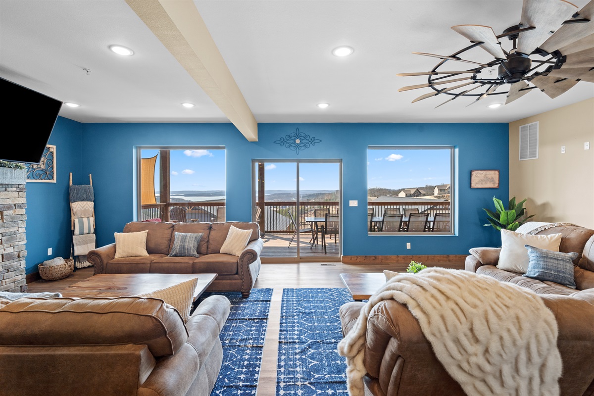 Relax in the bright great room with fireplace, plenty of seating, and deck access with lake views