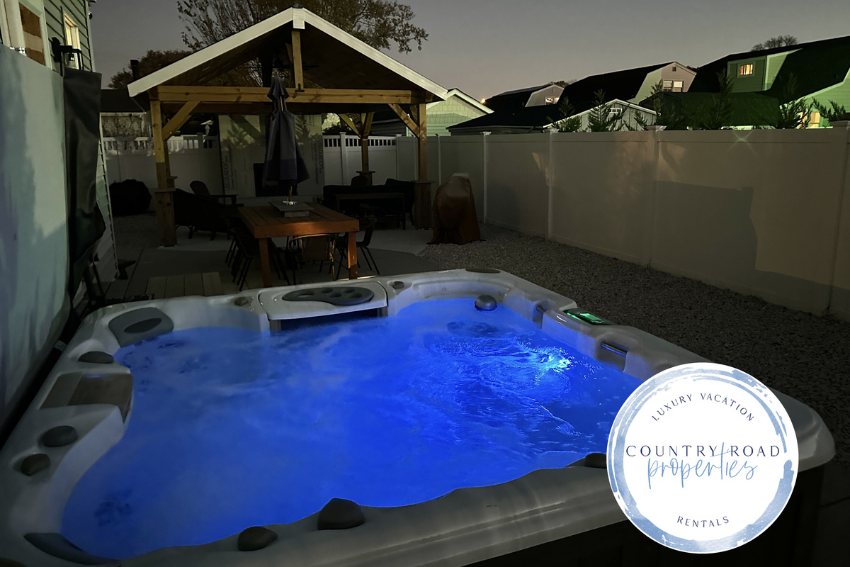 Indulge in ultimate relaxation under the stars in our glowing blue hot tub. This private backyard oasis features a spacious patio with a dining table and a covered lounge, perfect for soothing escapes during your vacation.