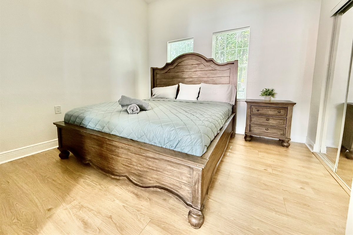 Earth-toned textures meet natural light in this warm and welcoming bedroom—complete with a grand headboard and mirrored closet.