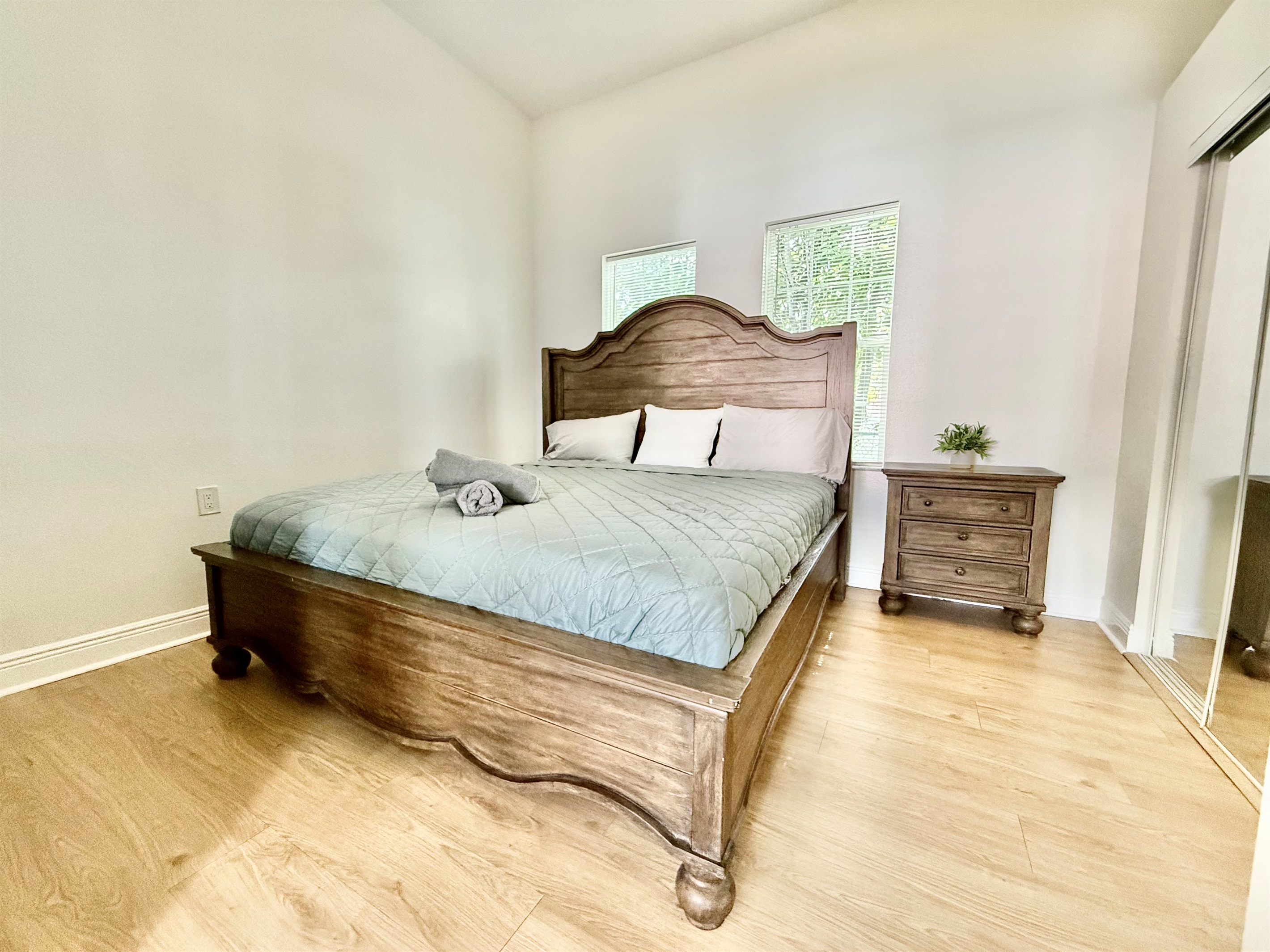 Earth-toned textures meet natural light in this warm and welcoming bedroom—complete with a grand headboard and mirrored closet.