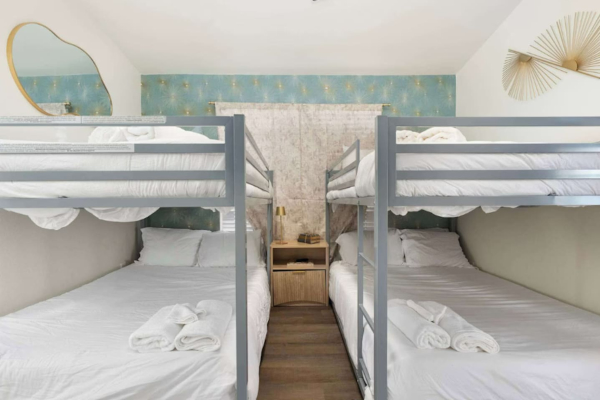 Quad bunk room with soft blue accents, white bedding, and modern finishes—sleeps four guests in comfortable style.