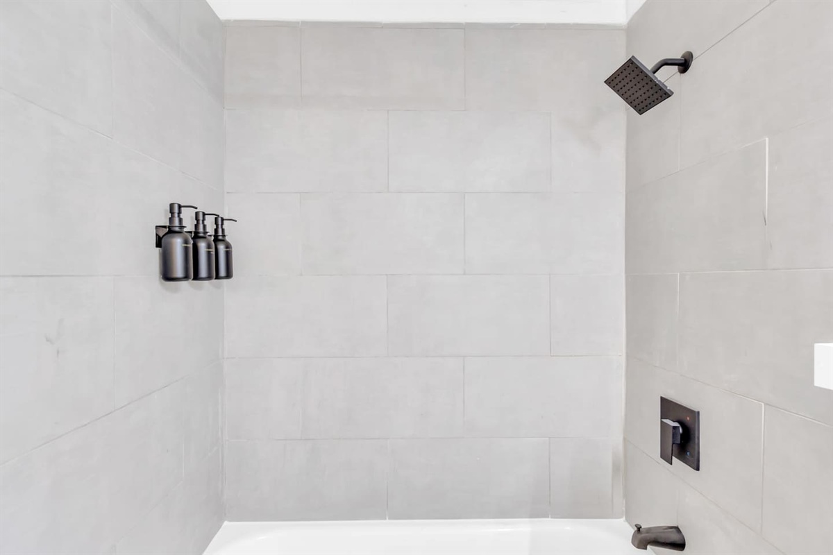 Bathroom with shower/tub combo, premium Ginger Lily Farms bath products, rainfall shower head,  and hotel-style touches.
