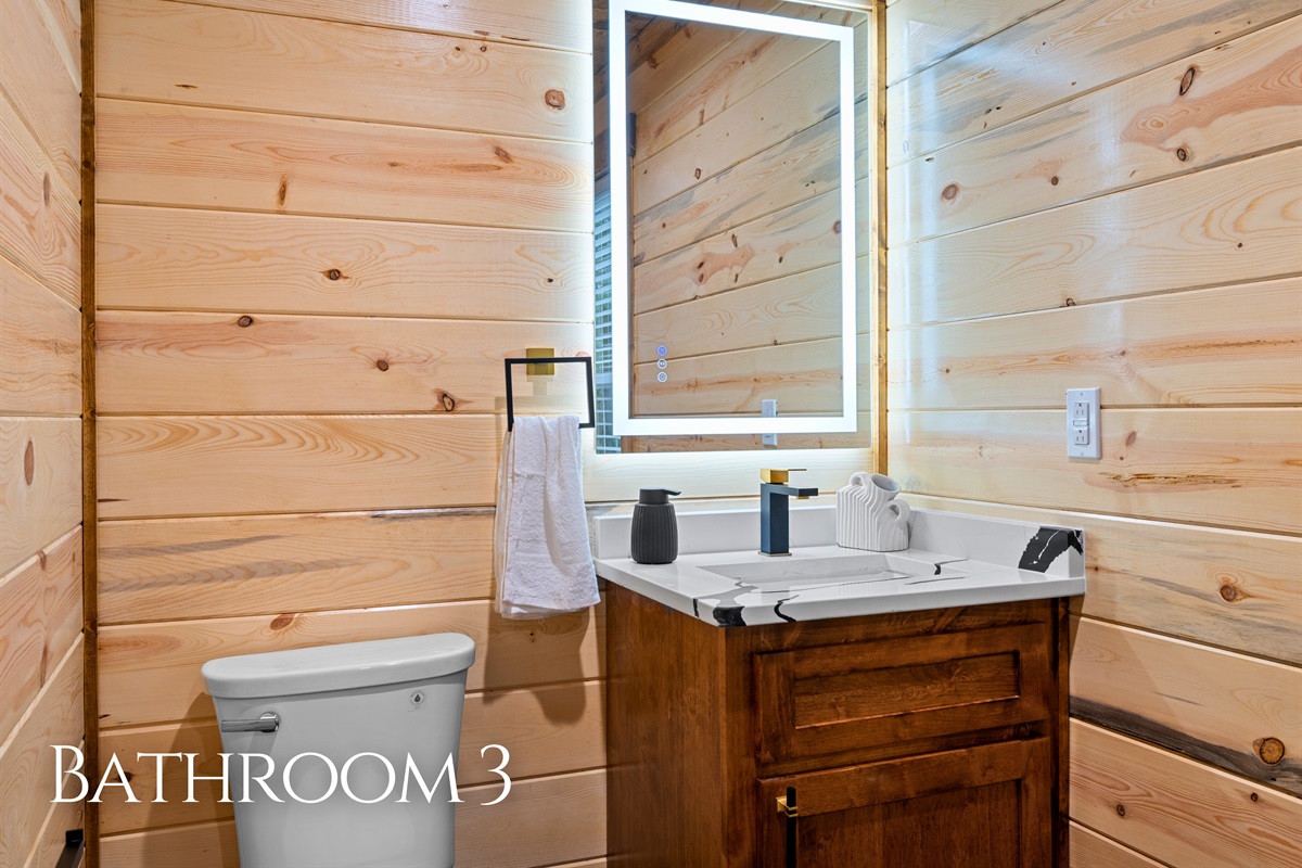 Located near the bunk area, this bathroom offers easy access for those staying upstairs while maintaining the same warm cabin finishes found throughout the home.