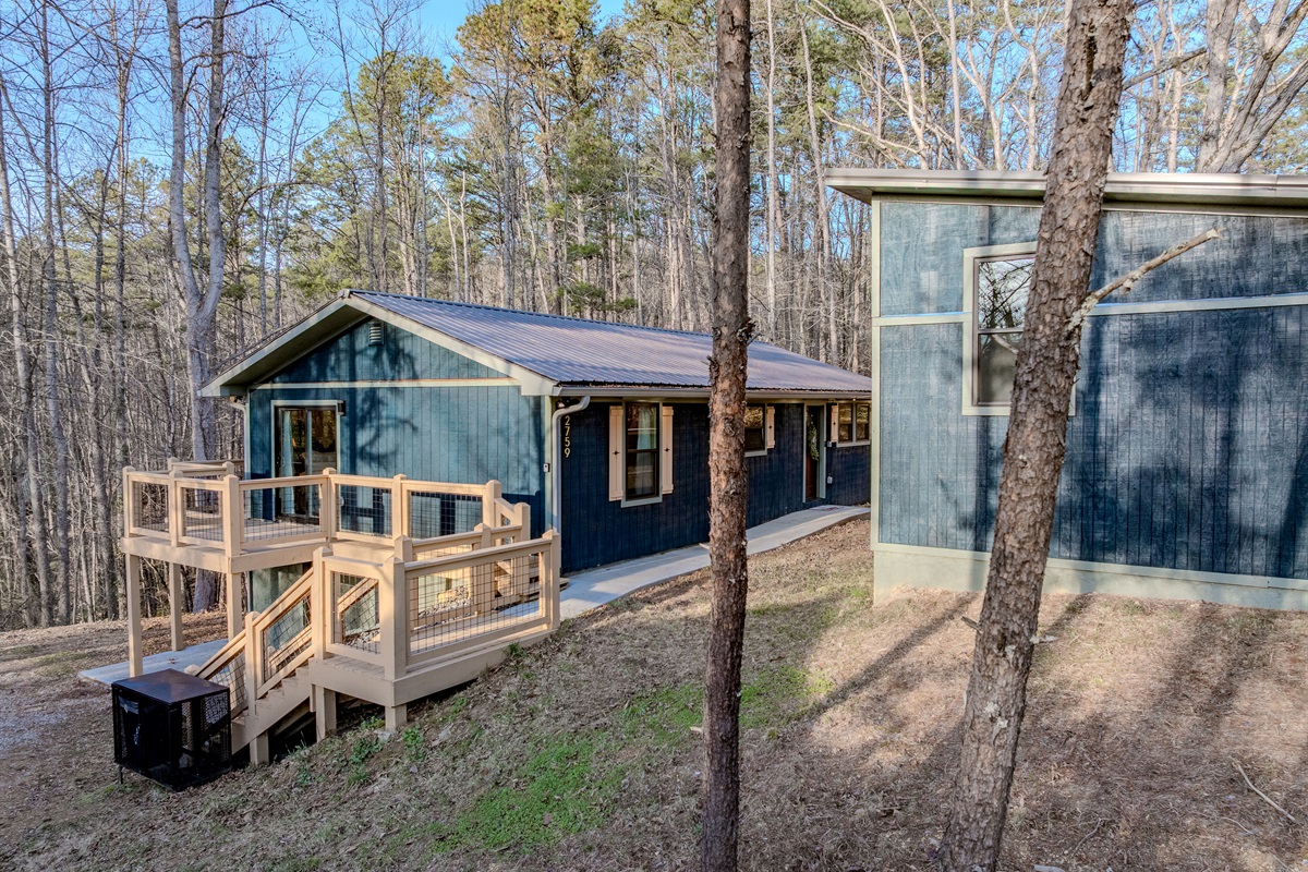 The striking blue exterior and tiered decking perfectly complement the natural beauty of the surrounding forest.