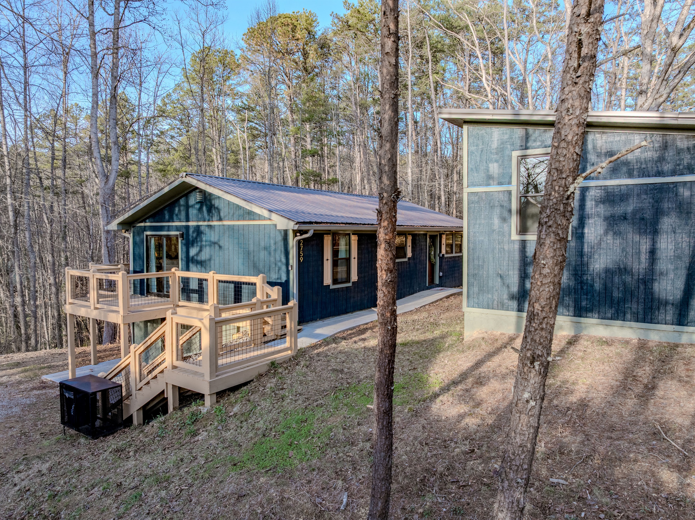 The striking blue exterior and tiered decking perfectly complement the natural beauty of the surrounding forest.
