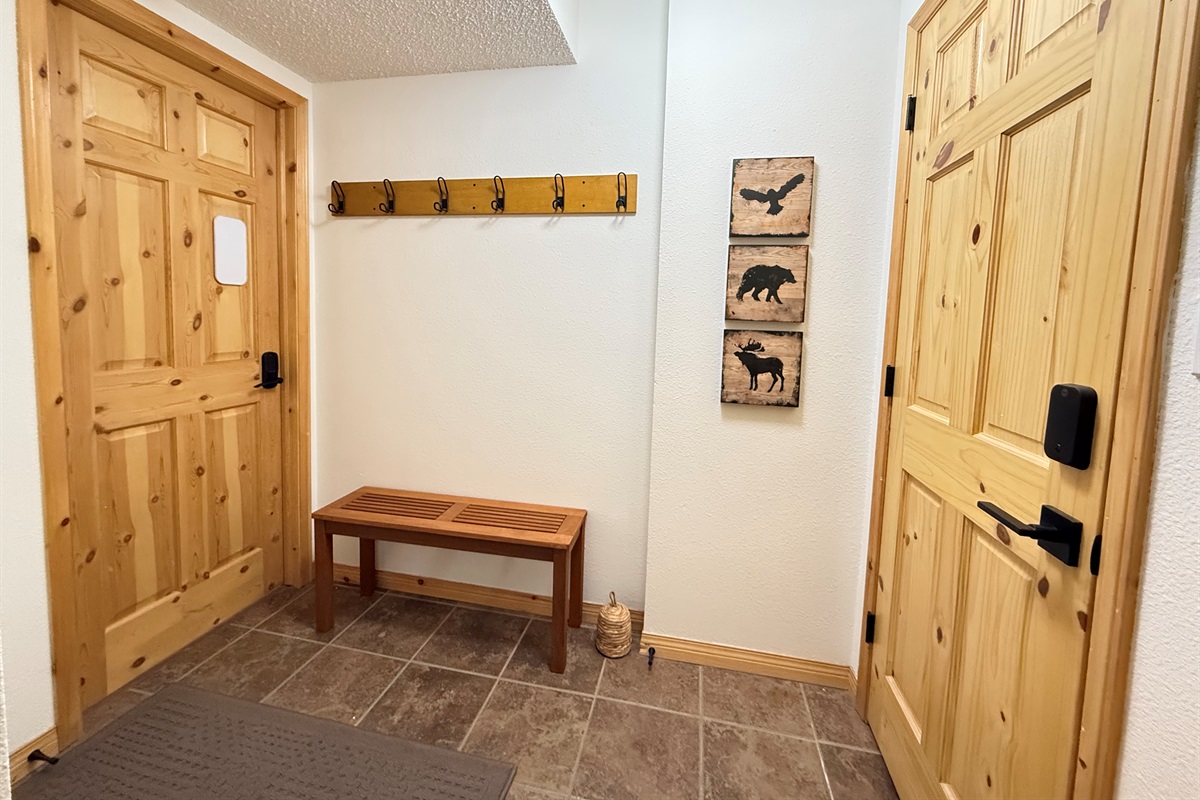 Efficient Entryway Storage: Compact and functional entrance at the Kimberley townhouse, featuring a wooden coat rack with ample hooks and floor space for boots. This entry is shared with the Bed & Bath suite (Left Door) and the Loft Suite (Right Door).