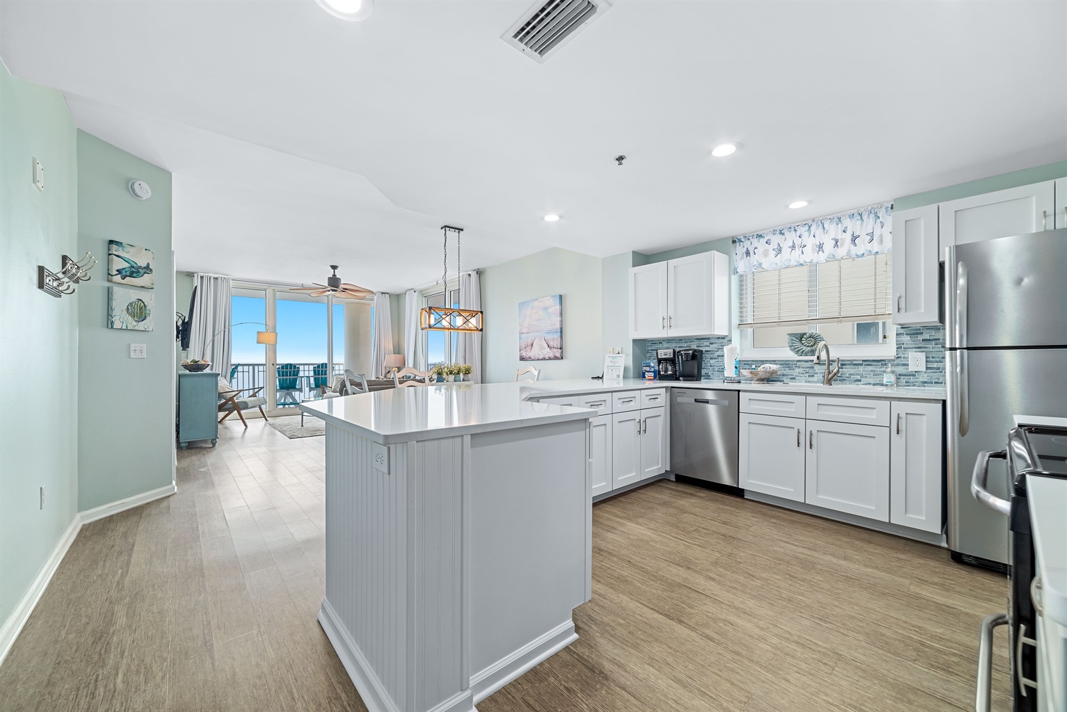 This bright, functional kitchen features white cabinetry, stainless steel appliances, and a seamless flow into the main living space. Enjoy the breathtaking Gulf view while brewing your morning coffee—it’s coastal living at its finest.