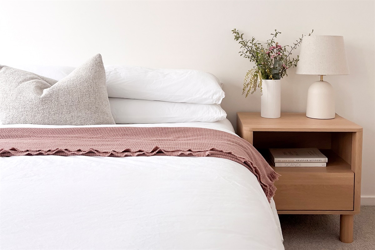 Fresh white bedding, a textured throw, bedside lamp and reading nook details give this queen room a tidy finish.