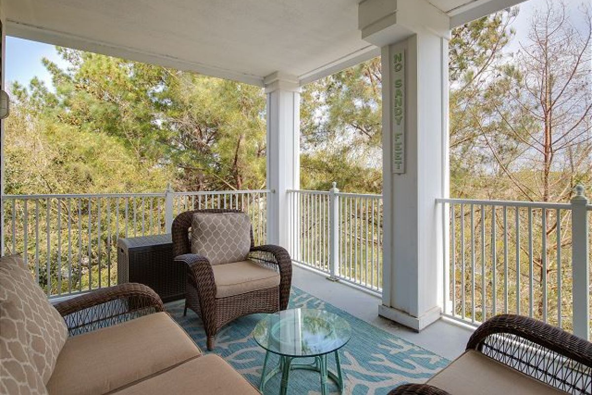 Covered balcony with wicker seating for four and resort garden views from the fourth floor