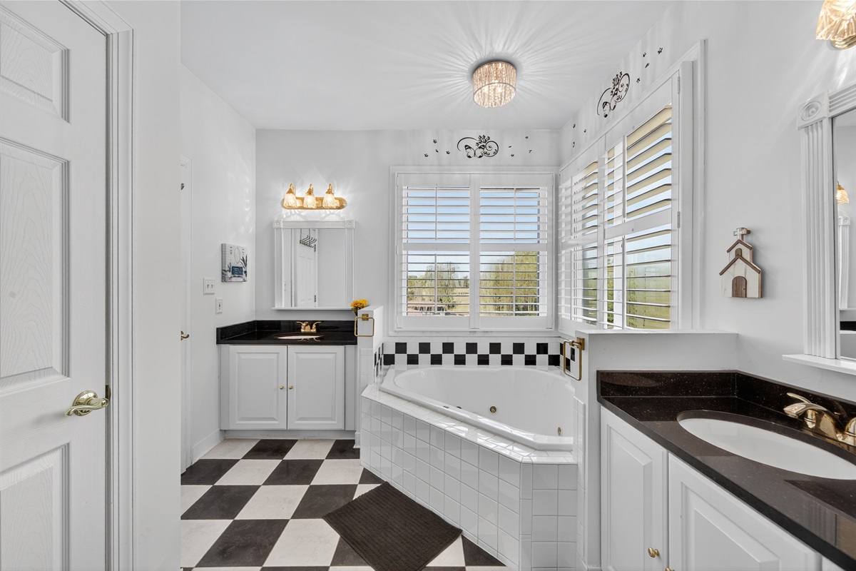 Spa-like primary bath with jetted tub and double vanities.