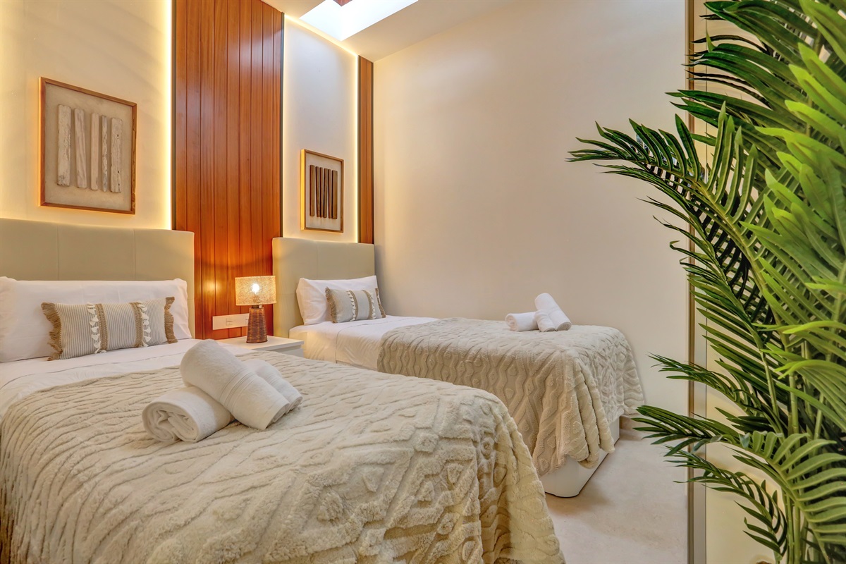 Charming second bedroom with two single beds, refined décor, and abundant natural light from exclusive electric skylight windows - a peaceful and inviting space for a perfect night’s rest.