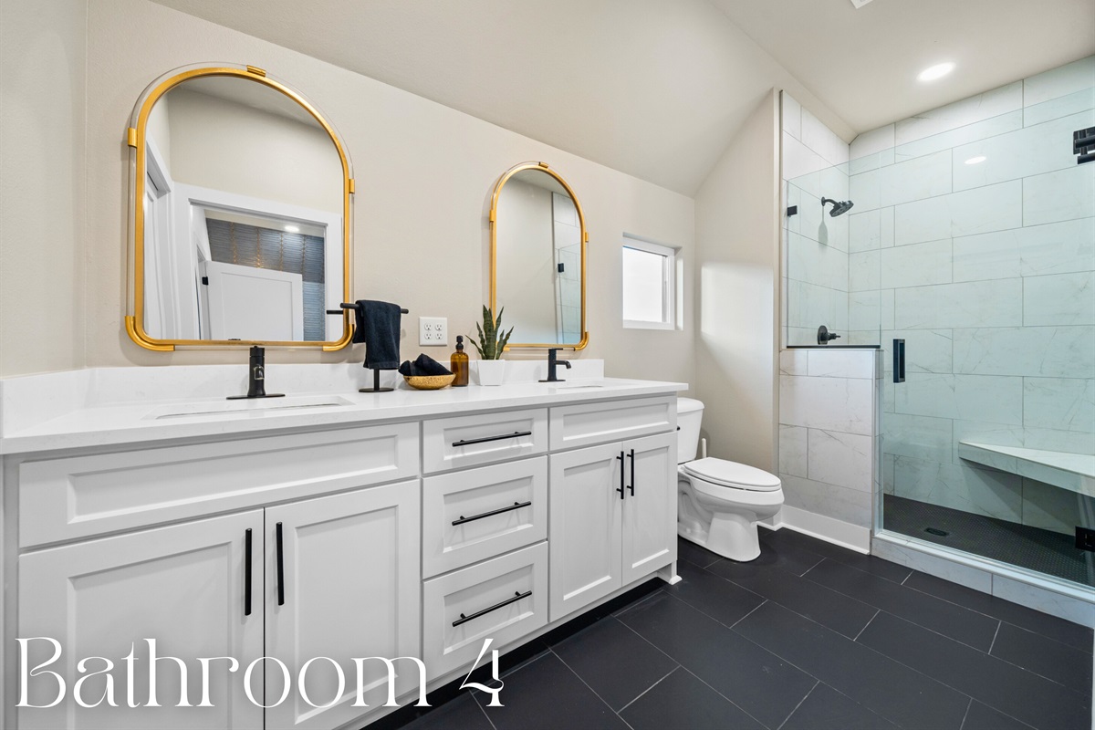 The elegant double vanity features gold-framed mirrors and sleek black fixtures, adding a touch of luxury.