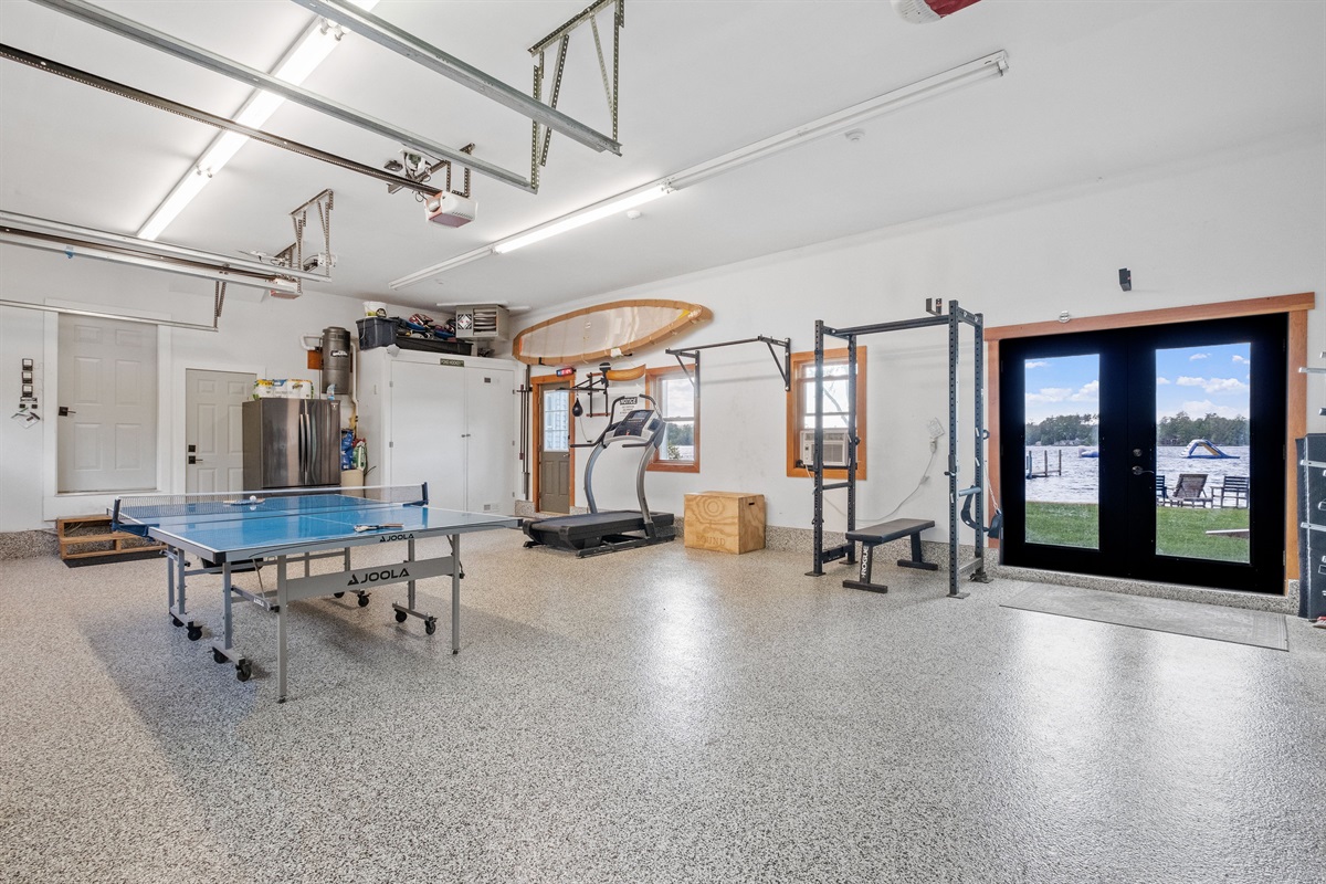 Garage with ping pong, parking for 3 cars, ev chargers, treadmill, and weights, also has a black light system and a bluetooth speaker