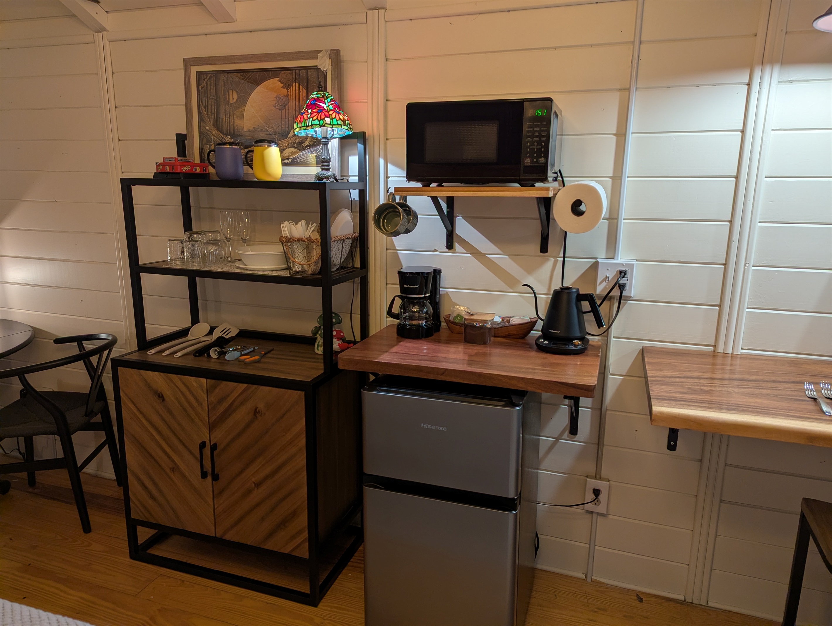 Mini Fridge with Freezer, microwave, drip coffee maker, electric kettle, plenty of dishes and drinkware. In cupboard is our electric burner with some pans and skillet. 