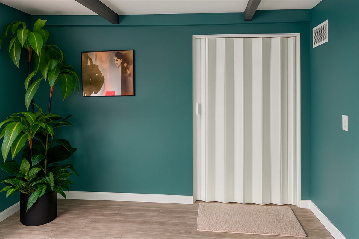 Private entrance corridor to The Gold Room at Garden of Manors, with modern teal walls and greenery welcoming you into the space.