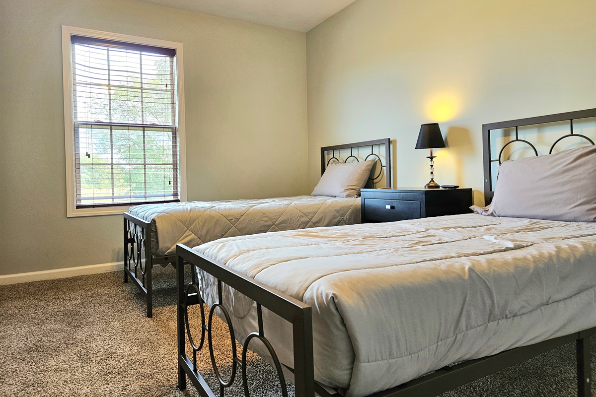 Guest room with two twin beds and large smart TV.