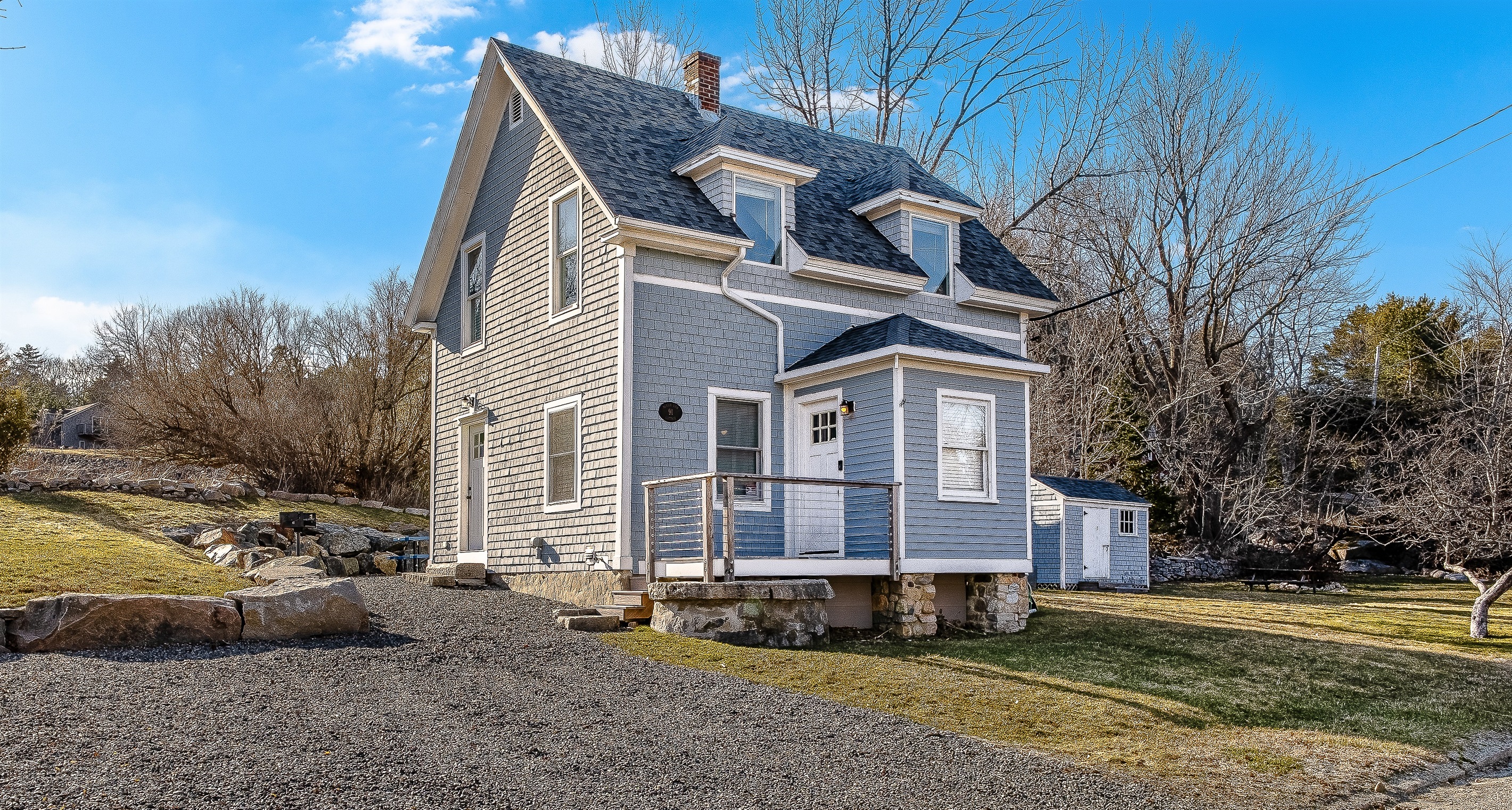 This driveway view shows the main entrance and mudroom—handy for dropping your boots after a hike. You can also see the side yard with the firepit, the perfect spot for roasting s'mores and planning your next trail under the stars.