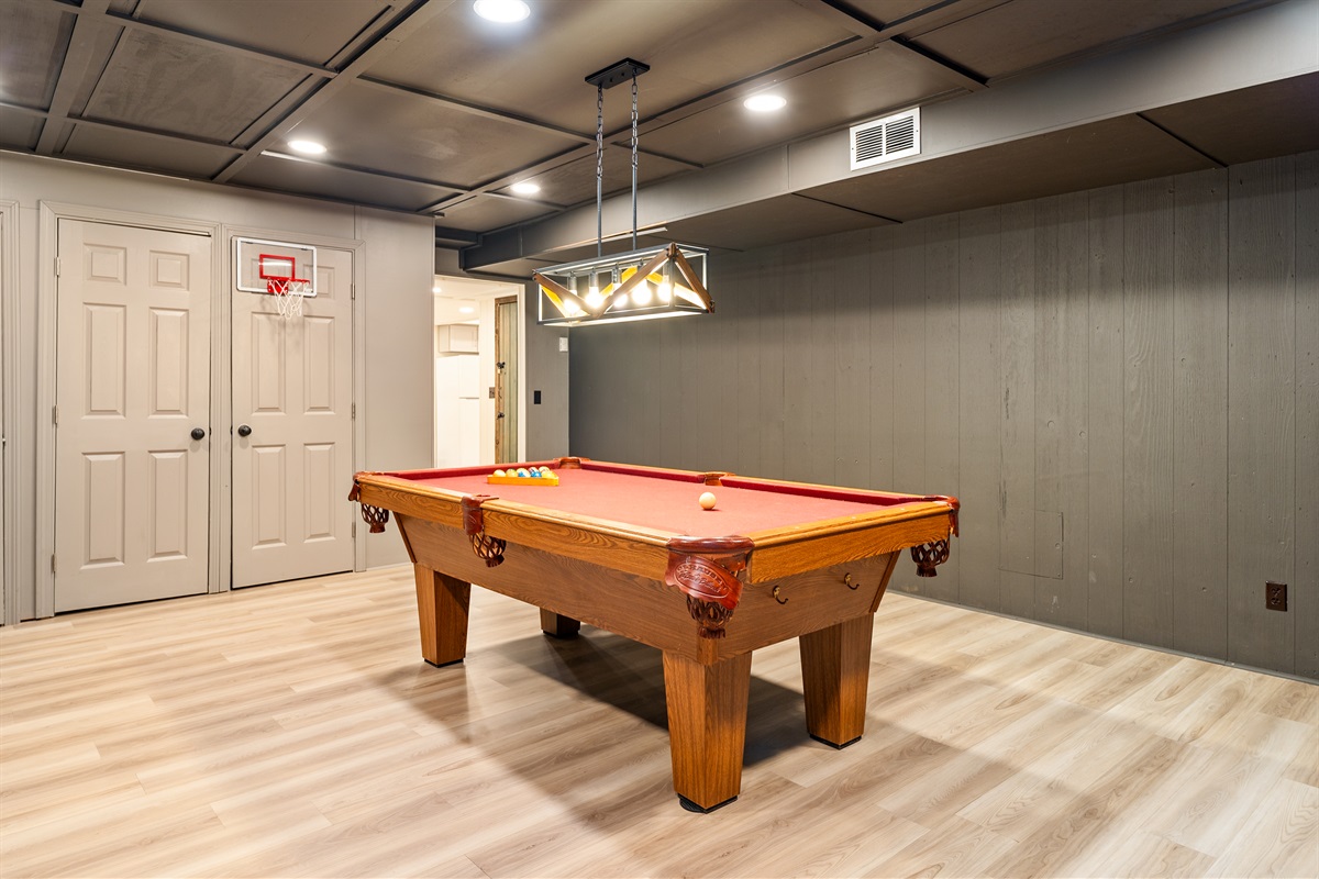Rack ’em up and enjoy friendly competition on the classic red felt pool table, set under stylish lighting.