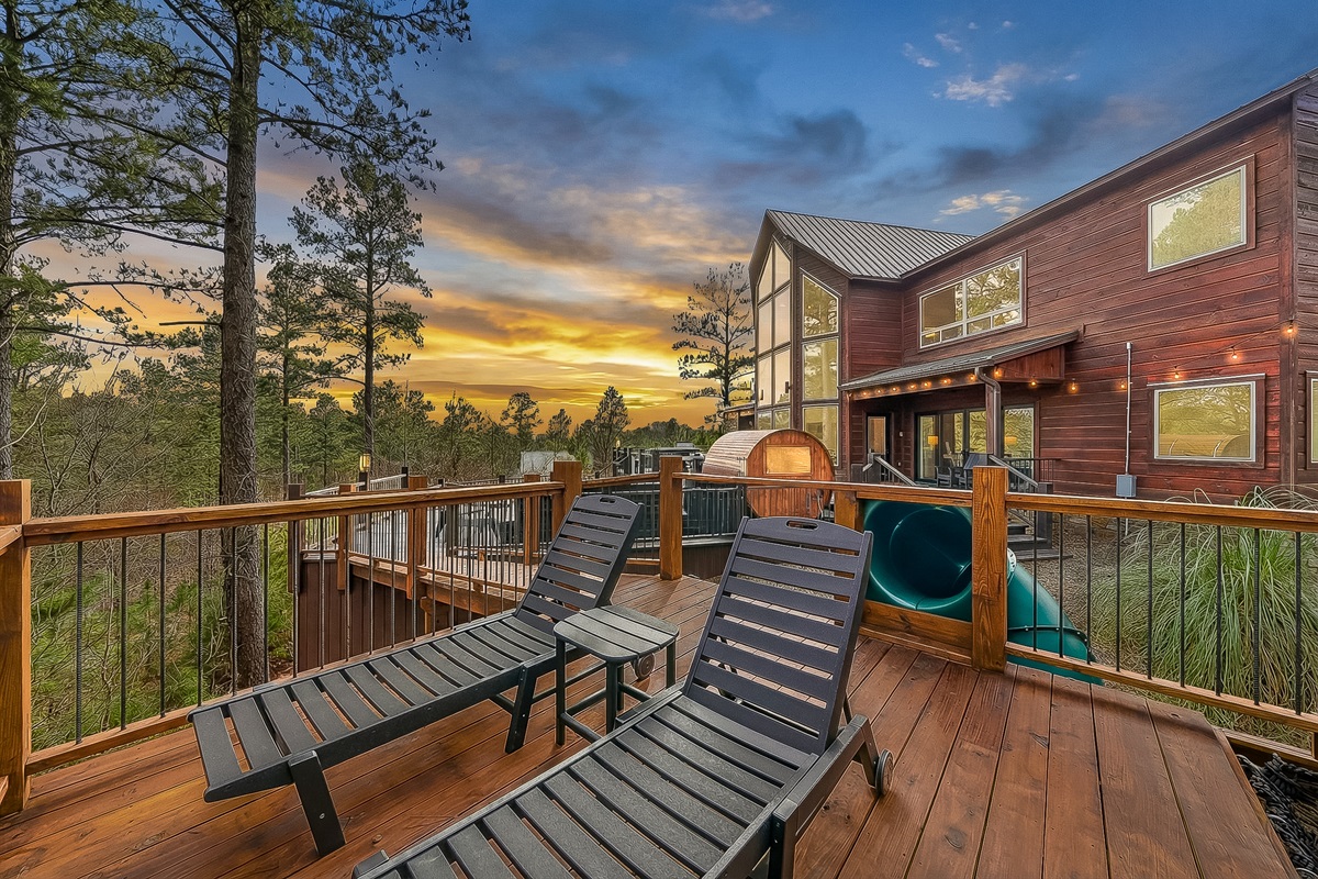 Elevated deck with cargo net hammock, lounge chairs, climbing wall and slide. 
