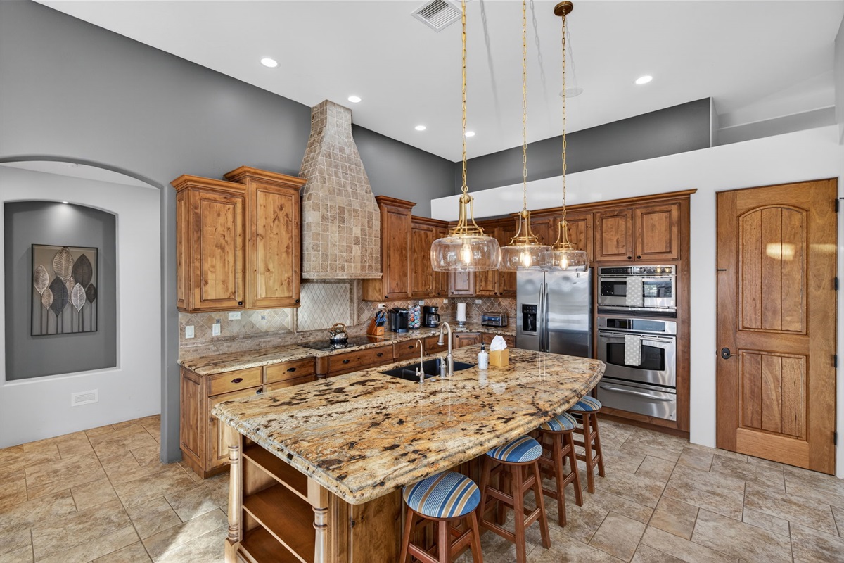 Luxury kitchen with granite island, custom cabinetry, and high-end appliances ready for your vacation feasts