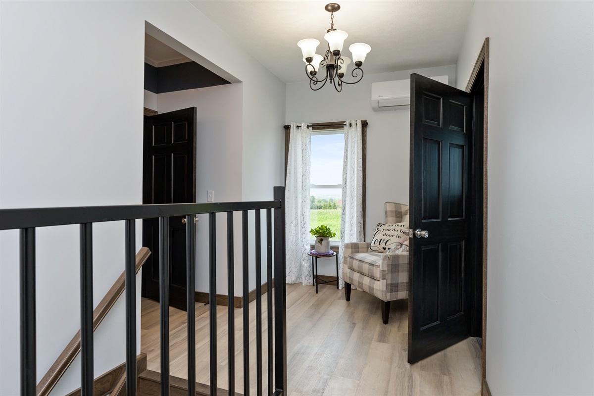 Bright upstairs landing with stylish sitting nook and modern chandelier, ideal for relaxing with a view.