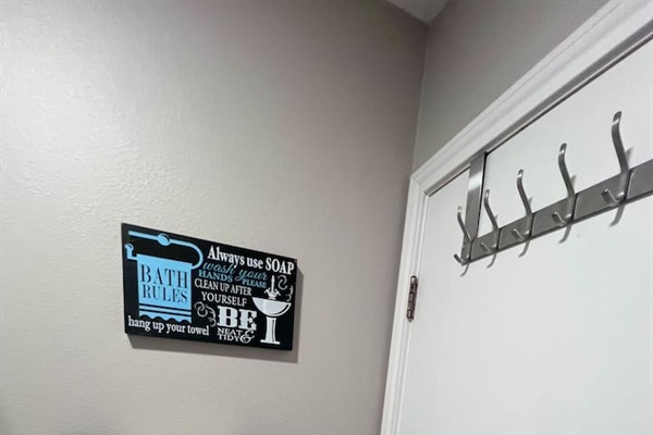 Bathroom detail with wall hooks and a reminder sign for guest use.
