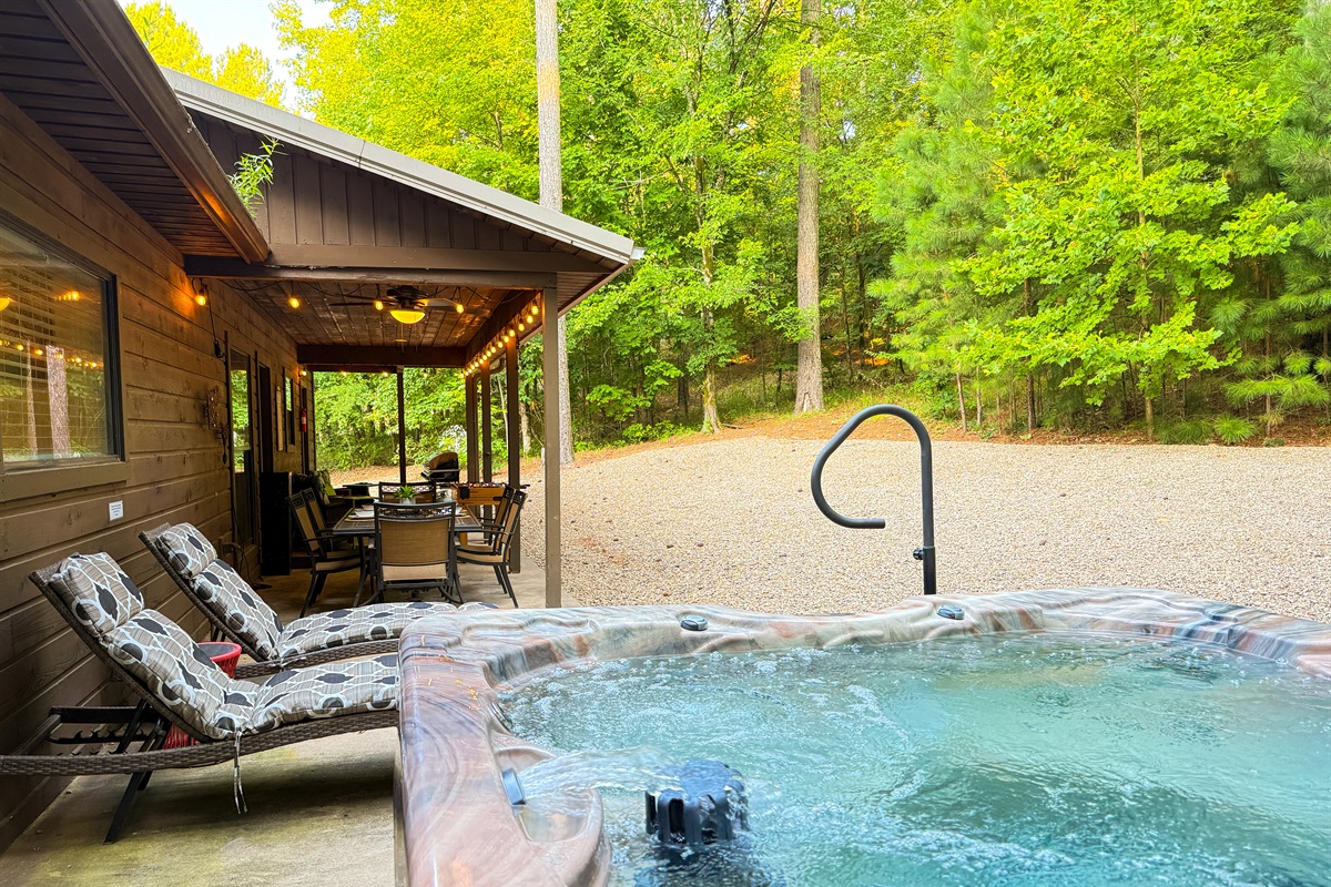 Relax in the private hot tub with lounge chairs and forest views.