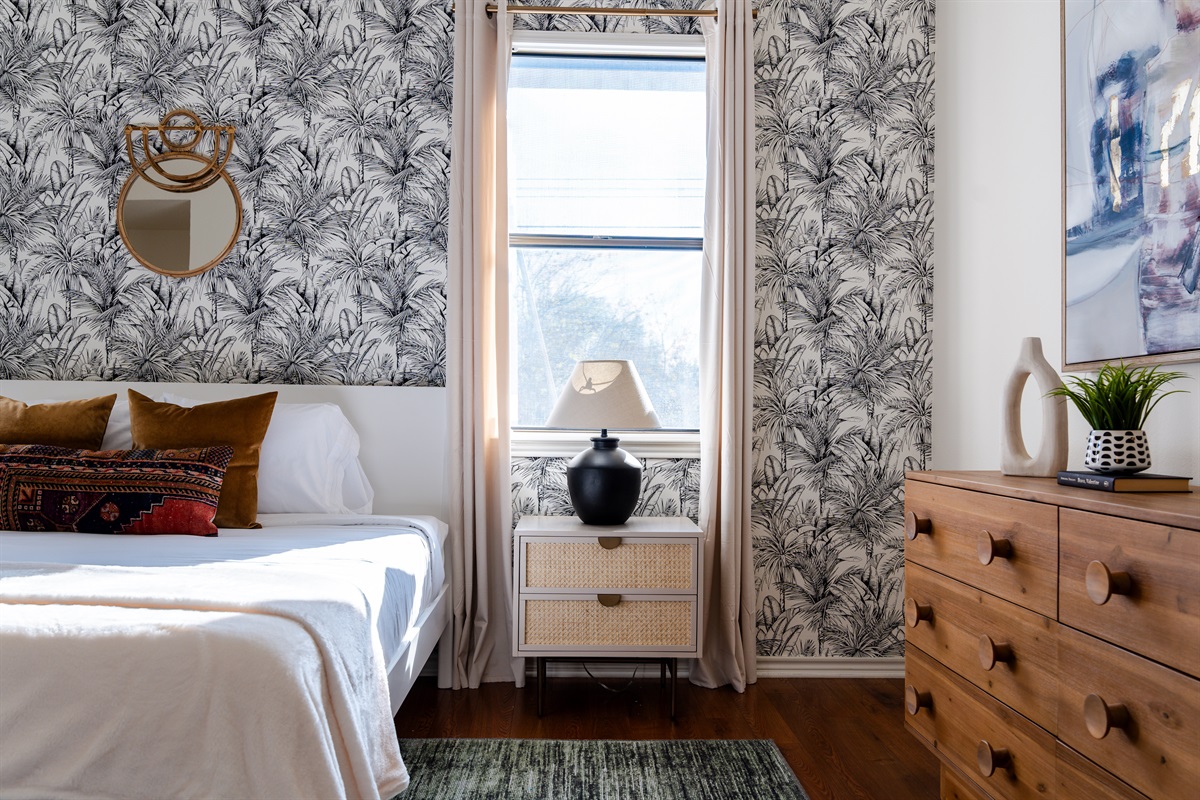 Elegant bedroom featuring chic wallpaper, a soft bedside glow, and inviting bed with comfortable linens.