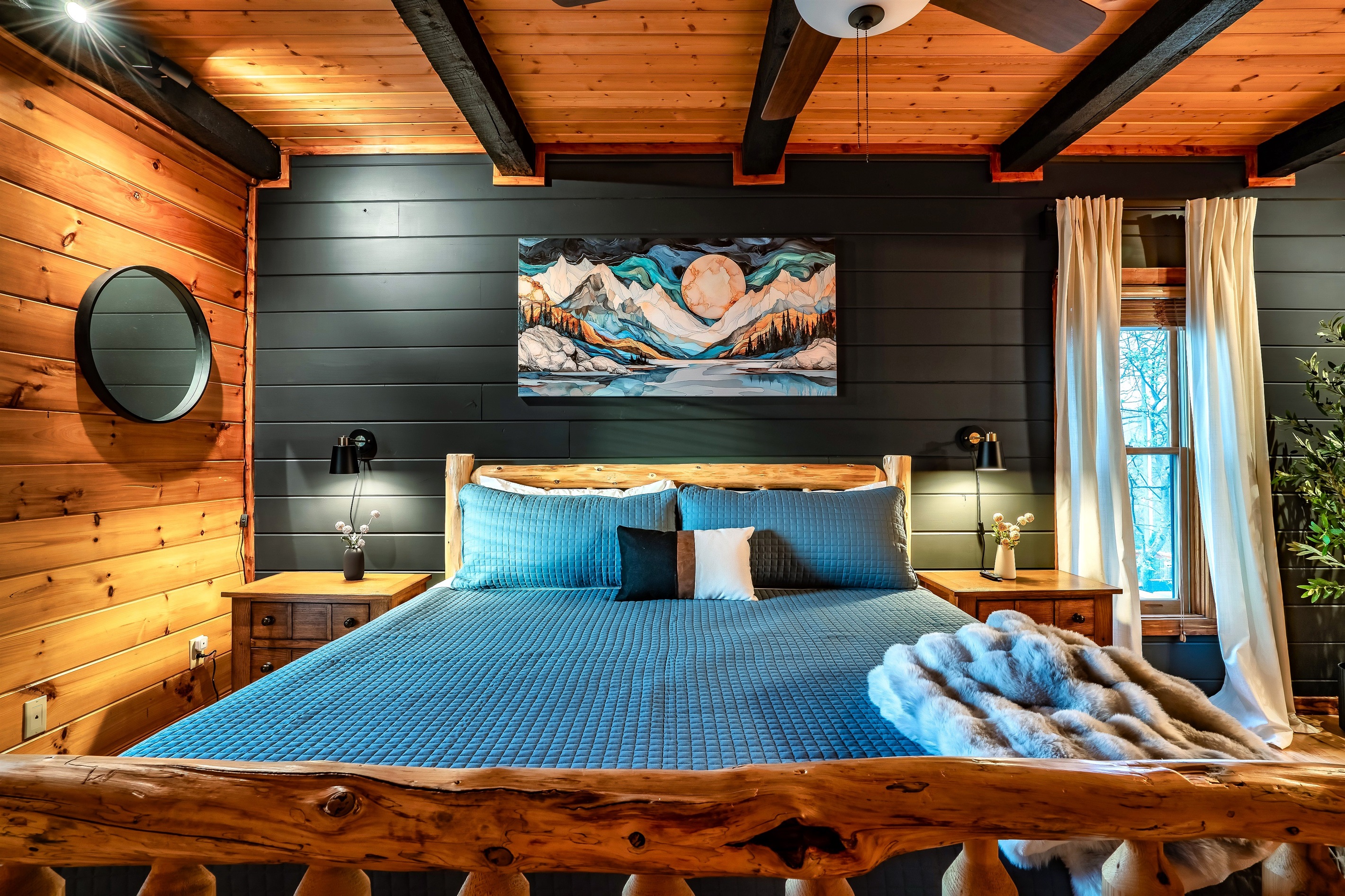 Cozy yet modern master bedroom in a mountain cabin, featuring a bold darkened accent wall and plush bedding for ultimate relaxation and comfort.