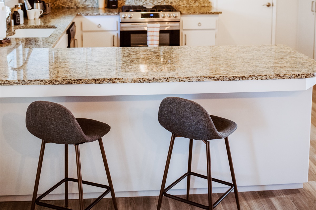 Enjoy a morning espresso at the sleek granite breakfast bar in this bright, modern kitchen.