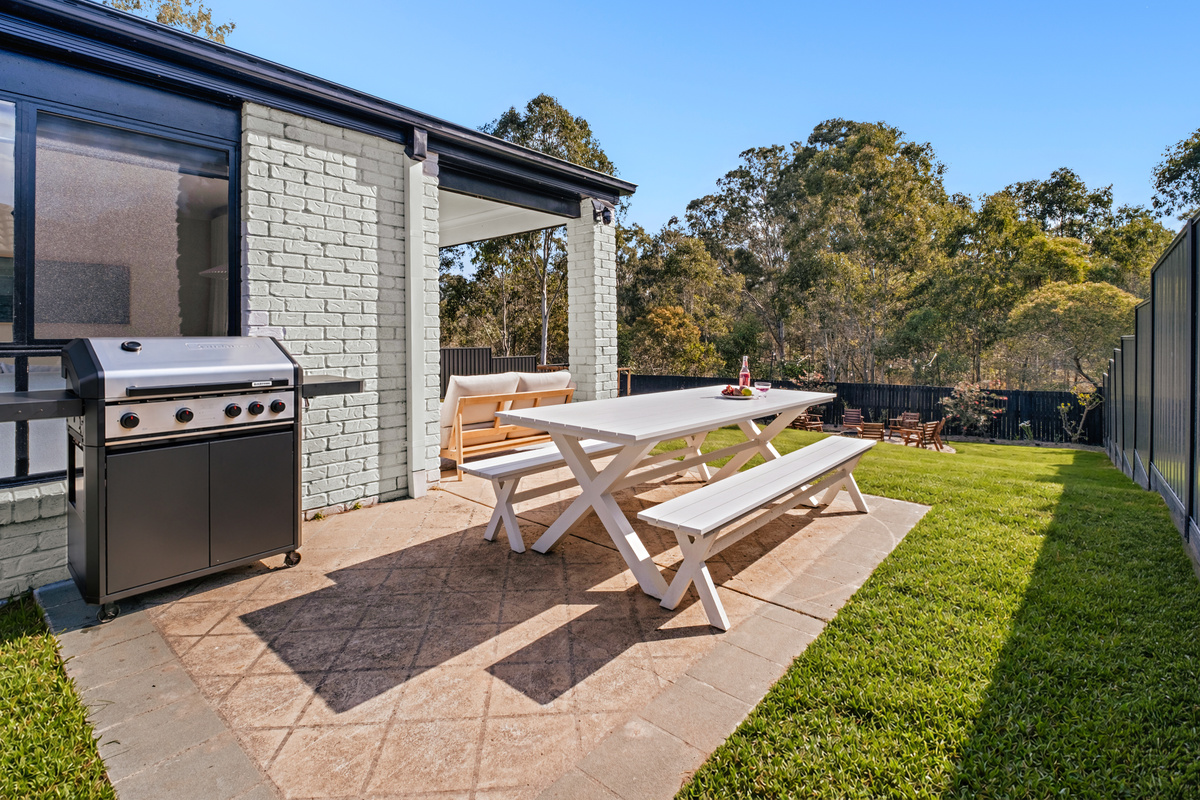 Enjoy outdoor dining surrounded by greenery, with a spacious table and BBQ ready for relaxed meals together.