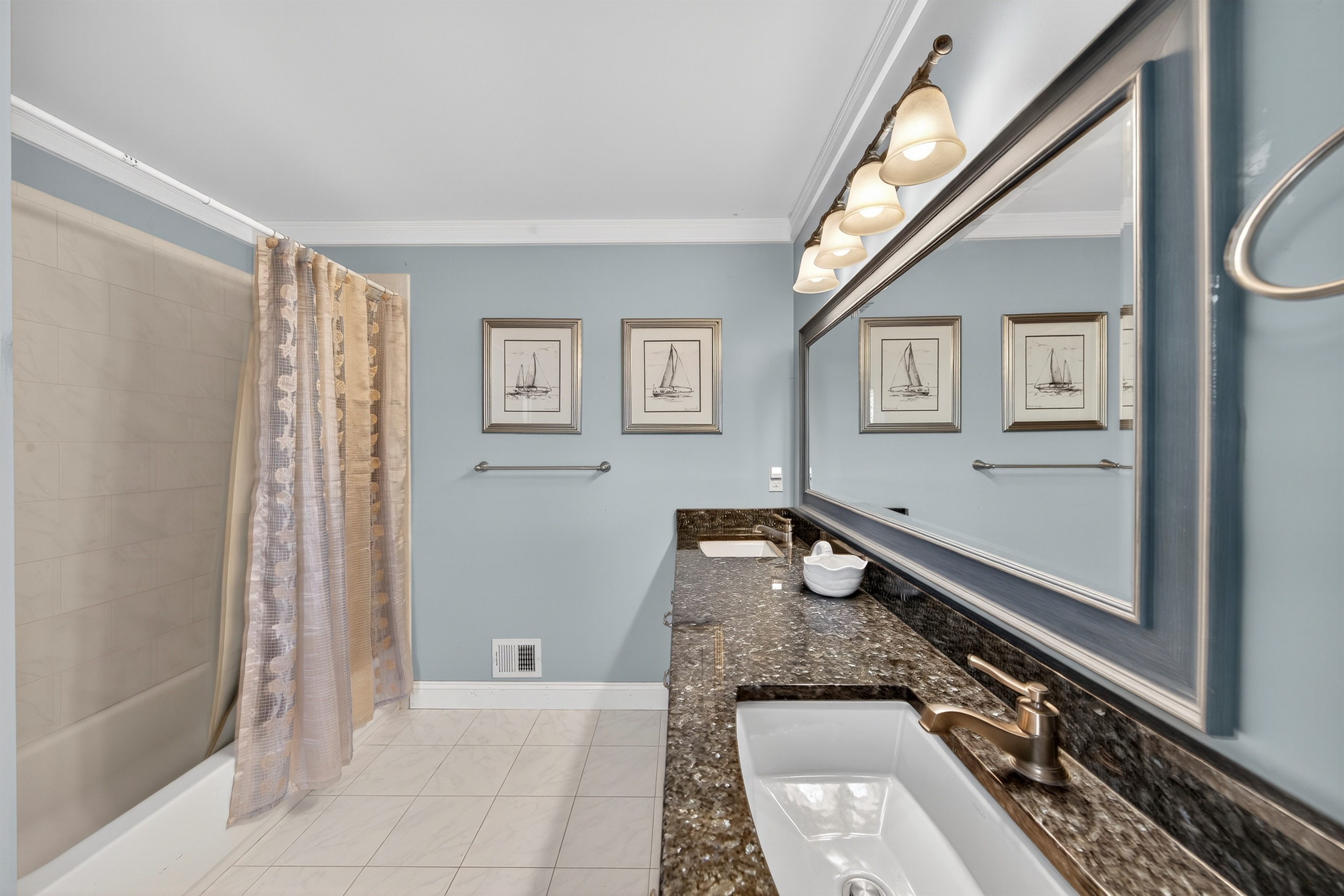 Coastal-inspired bathroom with a long granite vanity and warm bronze fixtures.