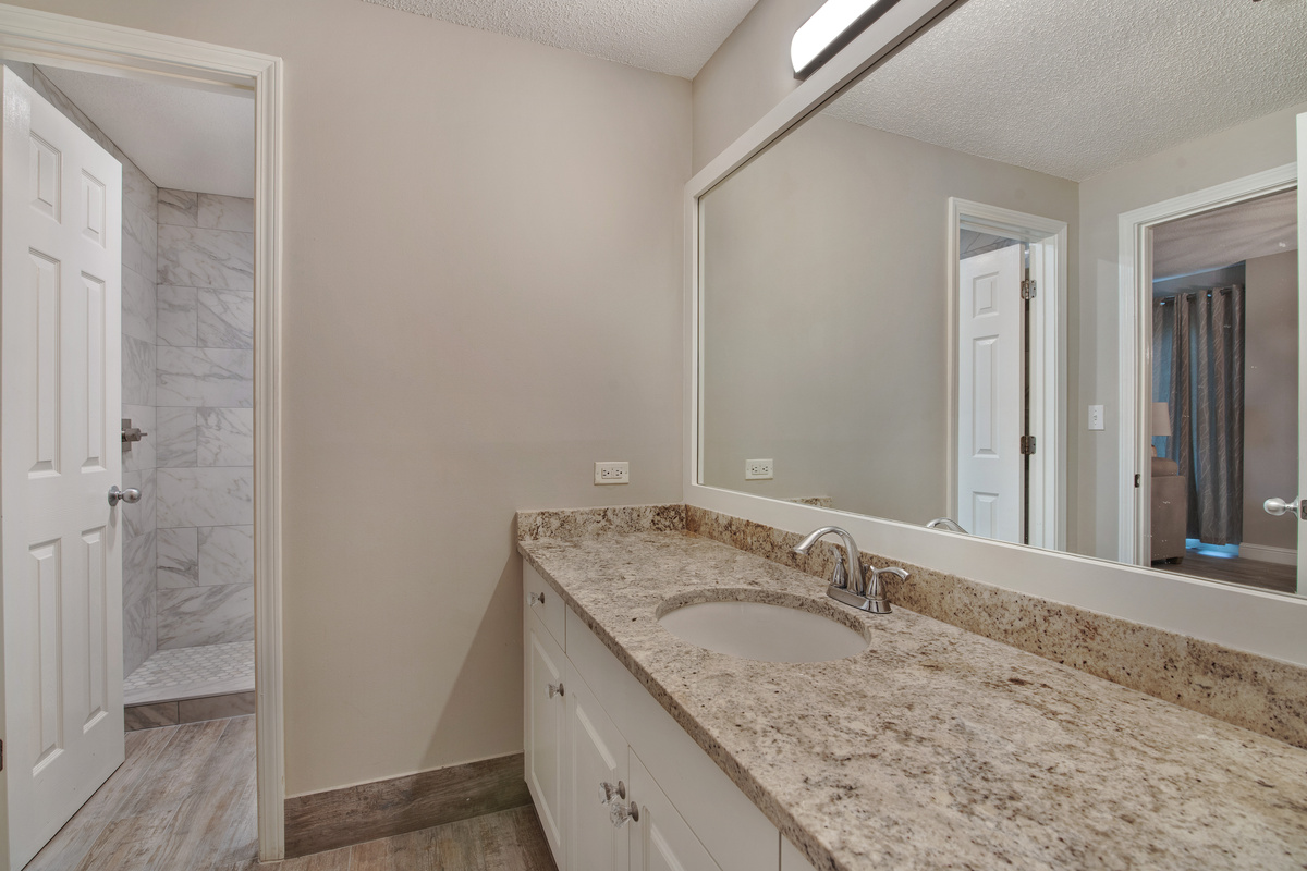 Guest bathroom with twin vanities and walk-shower accessible from living room