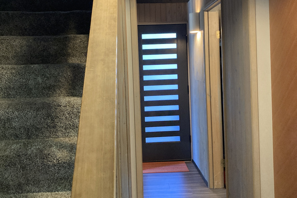 View down the hall from the kitchen of the door to the private hot tub deck! Downstairs bathroom to the right.