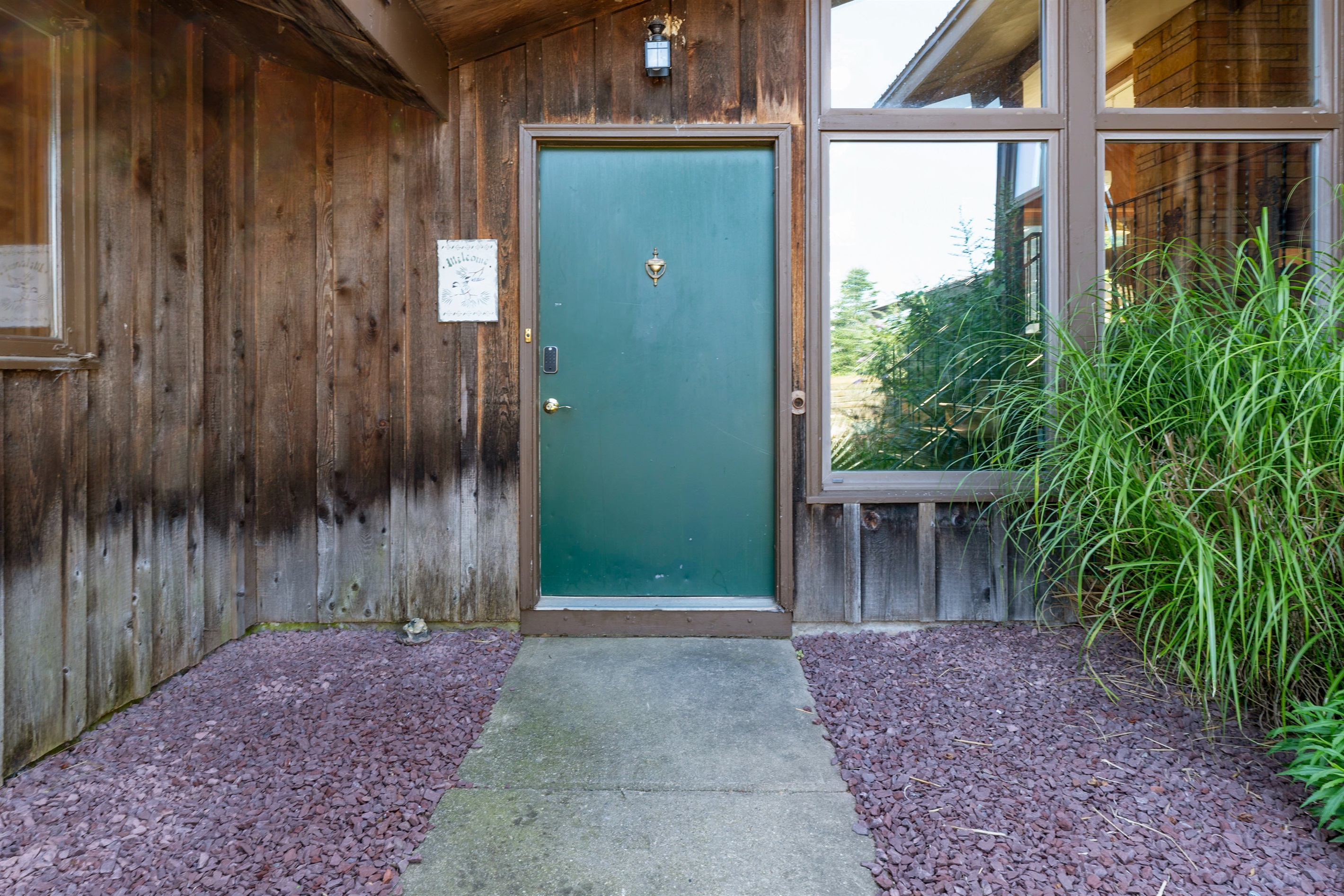 Rustic entry with bold green door and large windows welcoming natural light into the home.